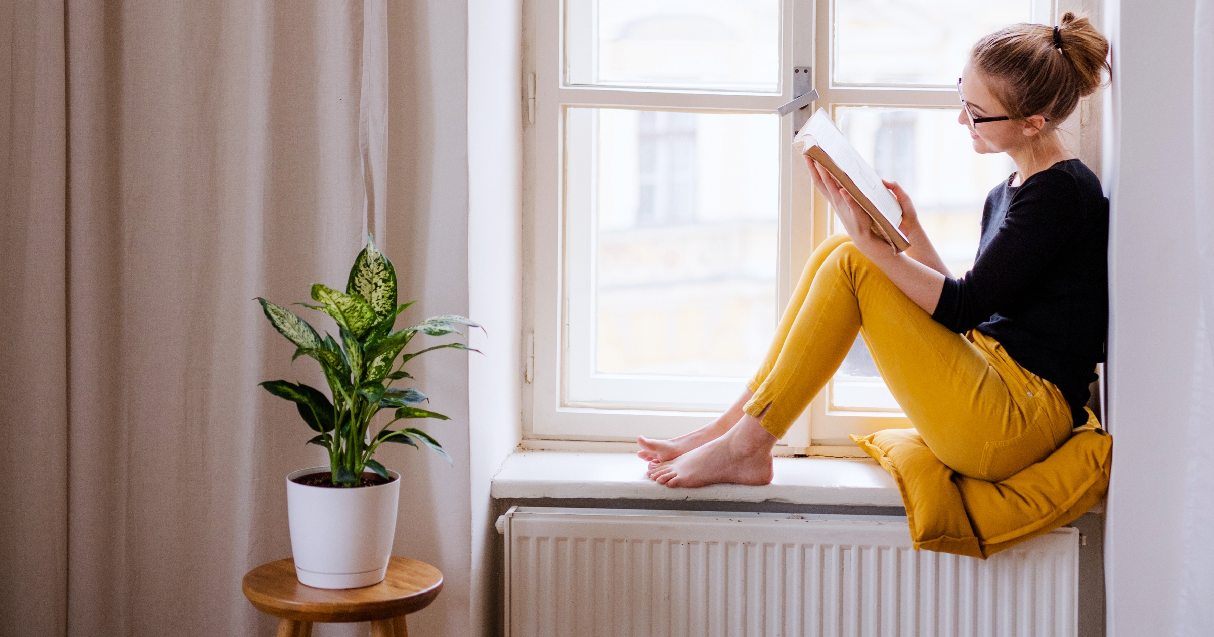 Girl reading a book on by the window